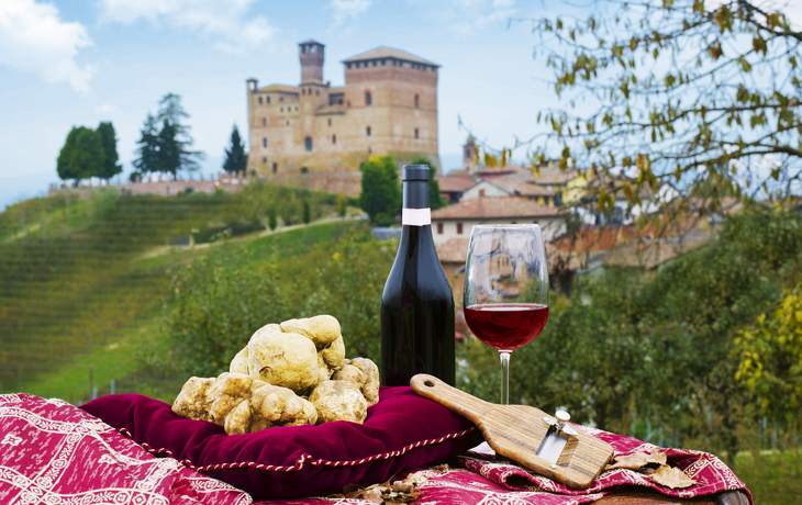 Weißtrüffel, Weinflasche und Glas vor italienischem Schloss und Landschaft.