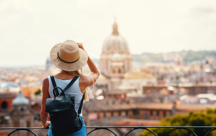 Eine Frau mit Hut und Rucksack genießt die Aussicht auf die Skyline von Rom, Italiens Hauptstadt.