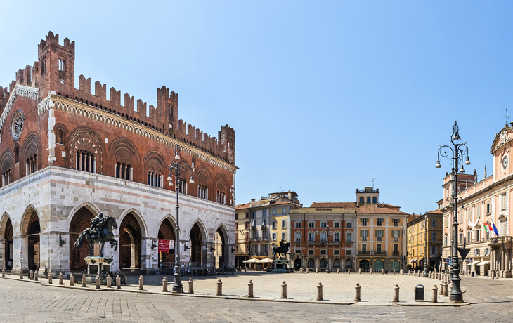 Piazza del Cavalli in Piacenza, Italien mit historischen Gebäuden und Statuen bei klarem Himmel.