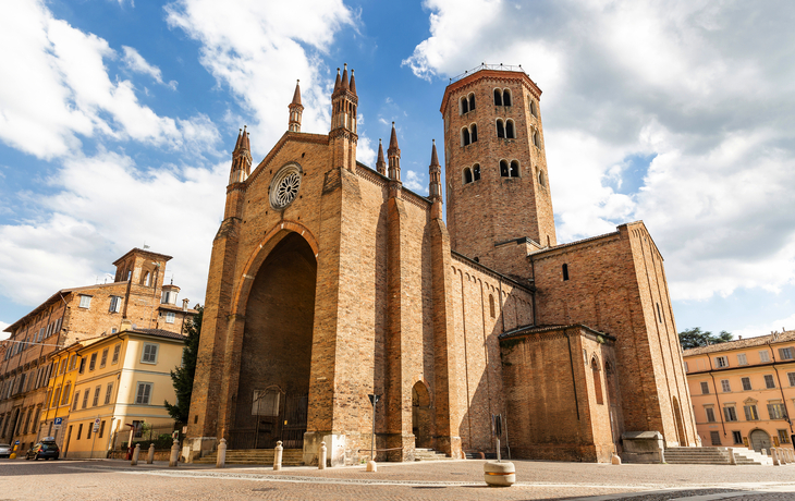 Basilika Sant'Antonino in Piacenza mit markantem Turm und gotischer Architektur unter blauem Himmel.