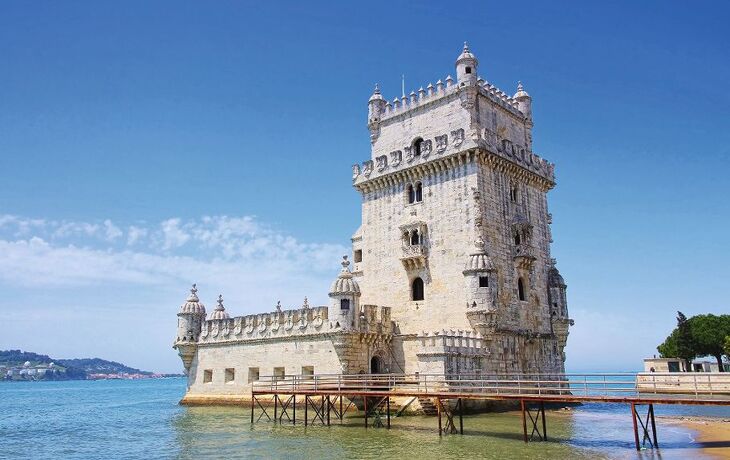 Historischer Turm am Wasser mit blauem Himmel.