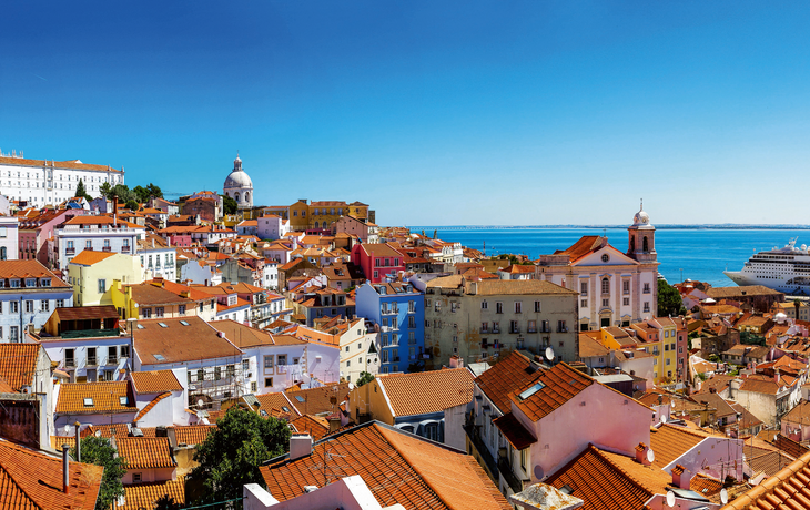 Panoramablick auf Lissabon mit roten Dächern und Kreuzfahrtschiff im Hafen.