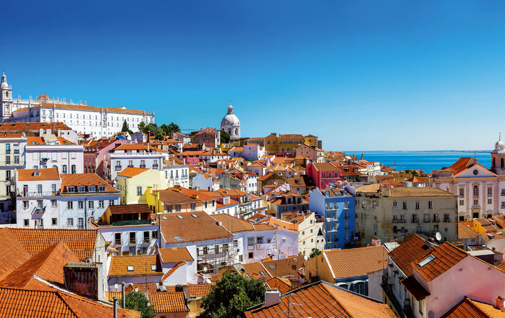 Panoramablick auf Lissabon mit roten Dächern und Kreuzfahrtschiff am Meer.