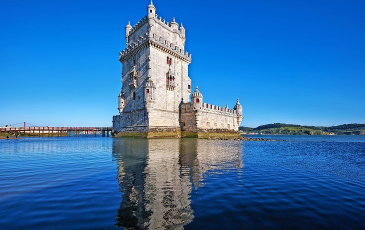 Historischer Turm am Wasser bei klarem Himmel.