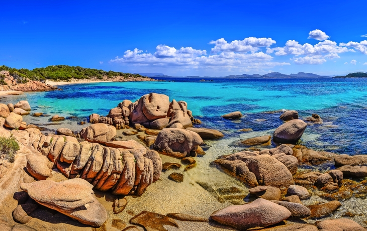 Felsen und türkisblaues Meer unter blauem Himmel an einer Küste.