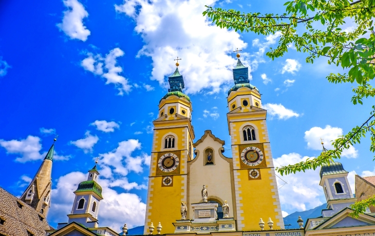 Barocke Kirche mit Doppeltürmen und blauem Himmel im Hintergrund.