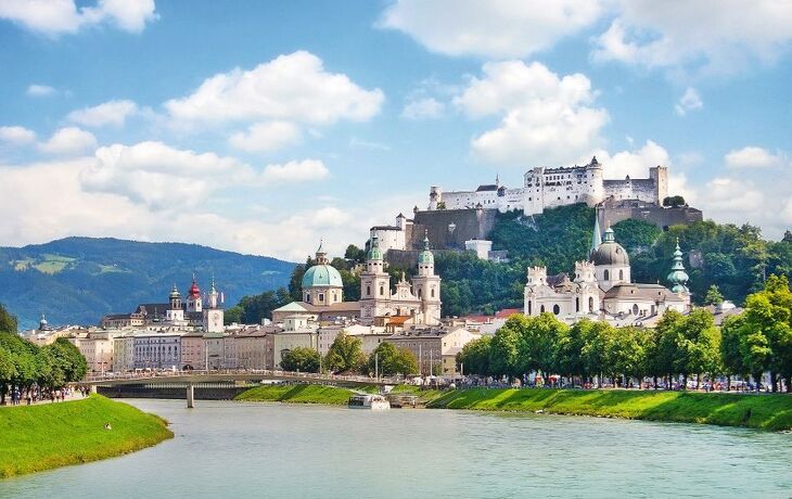 Stadtansicht von Salzburg mit Fluss und Festung Hohensalzburg im Hintergrund.