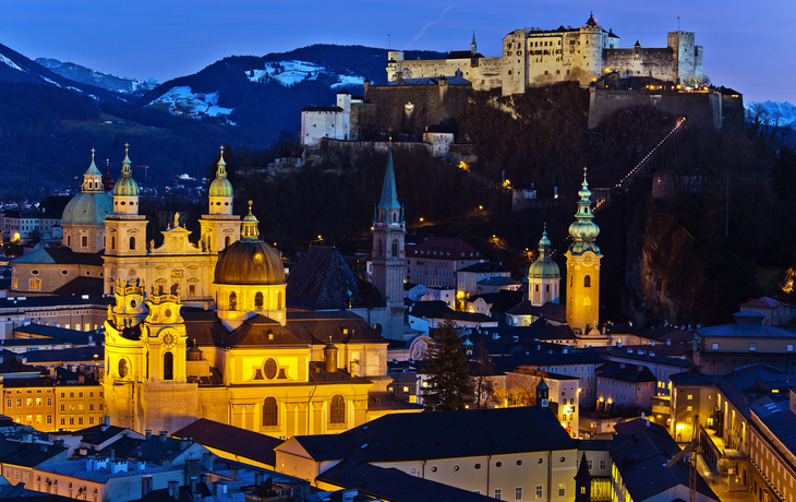 Blick auf Salzburg bei Dämmerung mit Festung Hohensalzburg im Hintergrund.