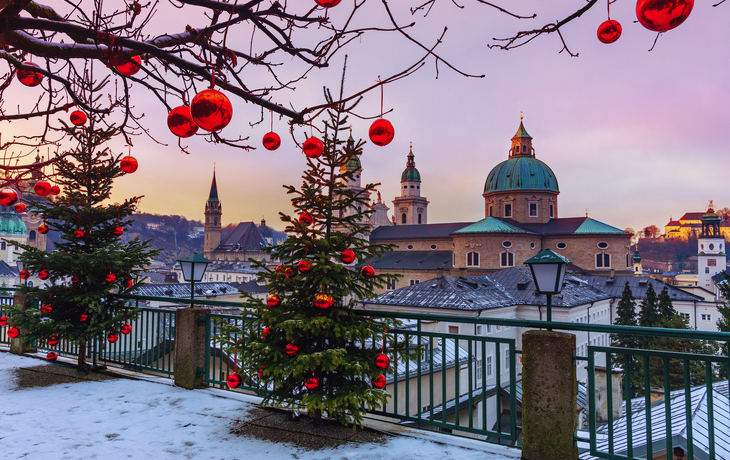 Winterlandschaft mit Weihnachtsbäumen und Kirche im Hintergrund.
