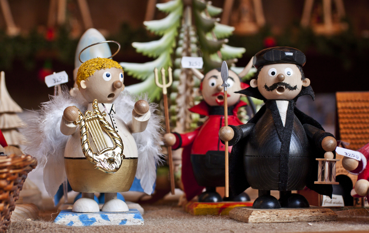 Holzfiguren von Engeln und Figuren in Weihnachtskostümen auf einem Markt.