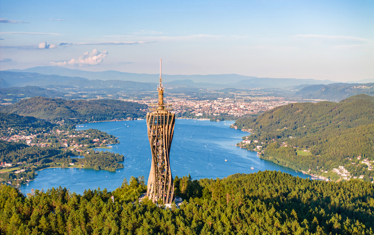 Aussicht vom Pyramidenkogel mit Blick auf den Wörthersee in Kärnten, umgeben von Wald und Bergen.