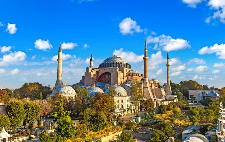 Historische Moschee mit vier Minaretten bei blauem Himmel.