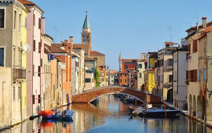 Kanal in einer italienischen Stadt mit Brücke und bunten Gebäuden.