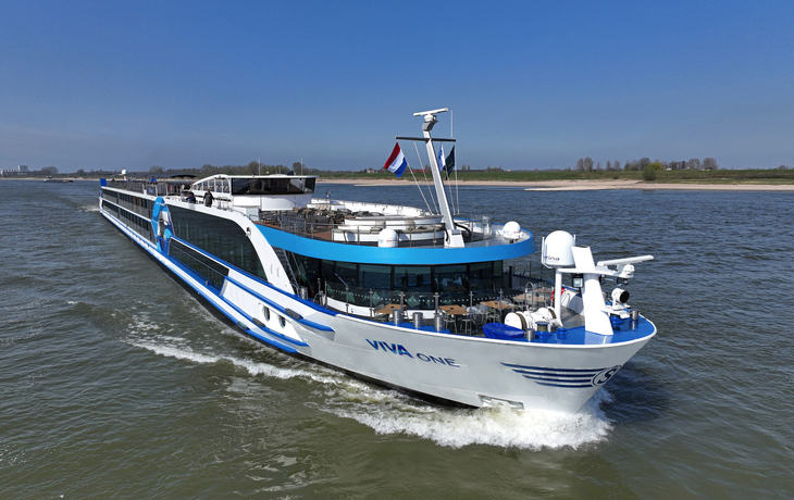 Flusskreuzfahrtschiff VIVA ONE auf einem Fluss mit klarem Himmel im Hintergrund.