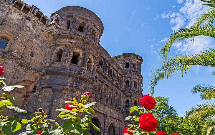 Alte Steinruine mit roten Rosen und blauem Himmel im Hintergrund.