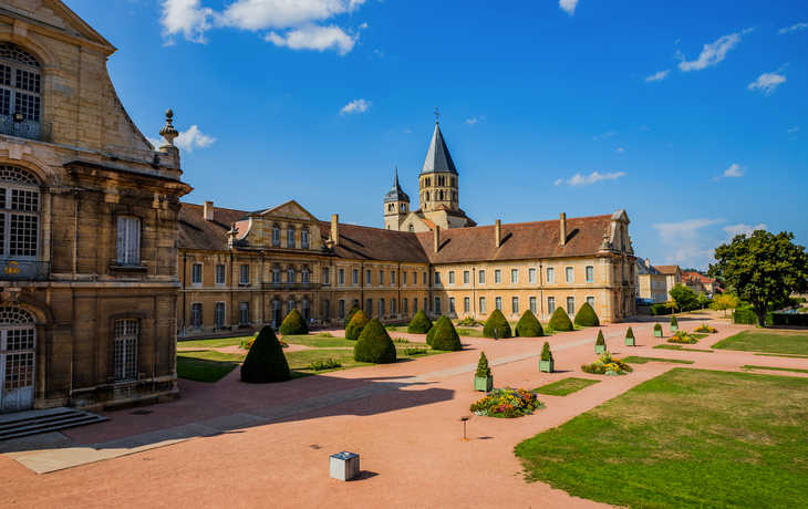Historisches Klostergebäude mit Garten und blauem Himmel.