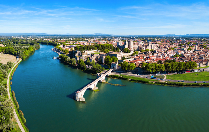 Luftaufnahme einer Flusslandschaft mit Stadt und Brücke bei klarem Himmel.